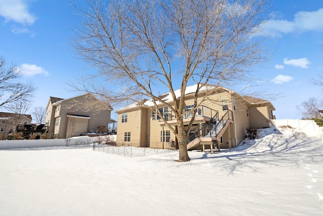 snow covered back of property featuring stairway