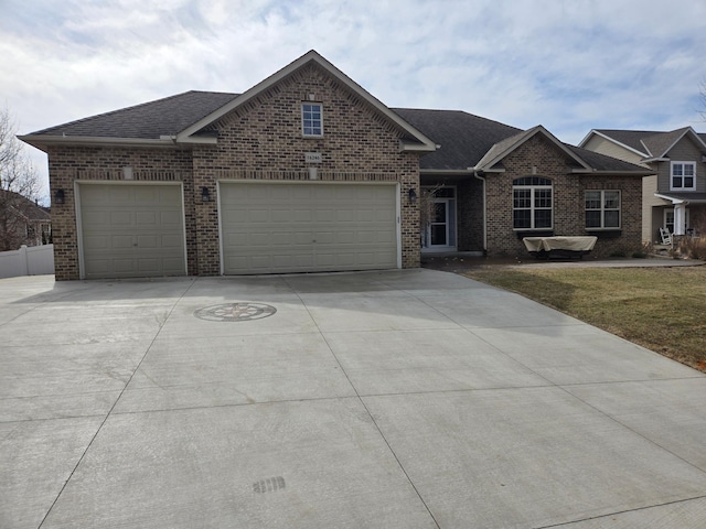 view of front facade with brick siding, an attached garage, roof with shingles, a front yard, and driveway