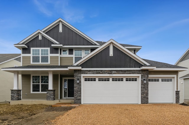 craftsman house with an attached garage, dirt driveway, board and batten siding, and roof with shingles