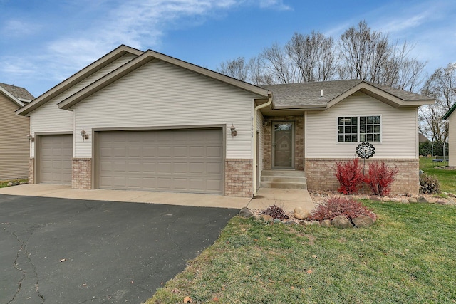 single story home featuring aphalt driveway, a front yard, brick siding, and an attached garage