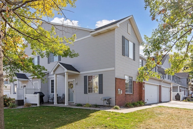 view of front of house featuring a garage, driveway, a front lawn, and brick siding