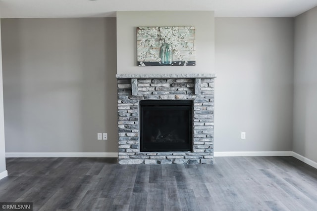 unfurnished living room featuring a stone fireplace, wood finished floors, and baseboards