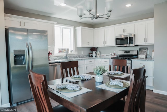 kitchen featuring white cabinets, light stone countertops, a chandelier, and stainless steel appliances