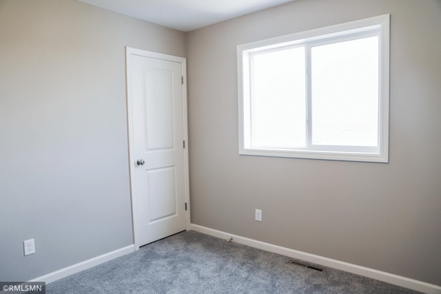 carpeted empty room with visible vents and baseboards