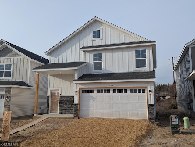 view of front facade with stone siding, board and batten siding, an attached garage, and a shingled roof