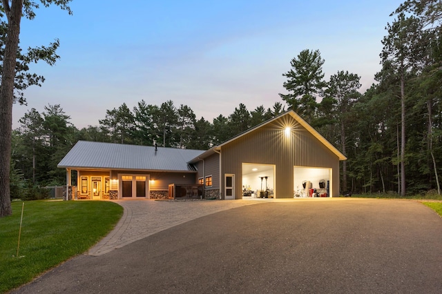 view of front facade featuring a front yard, stone siding, metal roof, and driveway