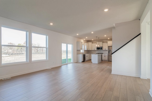 unfurnished living room with recessed lighting, visible vents, light wood-style flooring, and baseboards