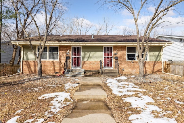 single story home featuring entry steps, brick siding, and fence