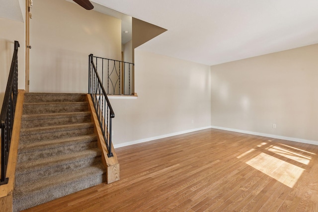 staircase featuring wood finished floors and baseboards