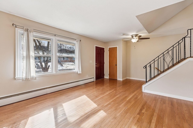 entrance foyer with baseboards, a ceiling fan, hardwood / wood-style flooring, a baseboard radiator, and stairway