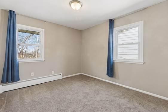 spare room with carpet floors, baseboards, and a baseboard heating unit