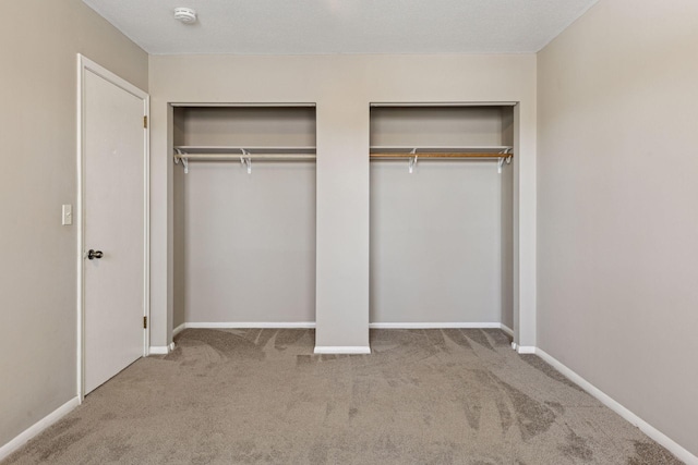 unfurnished bedroom with multiple closets, carpet, and baseboards