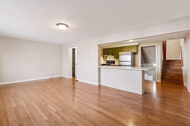 unfurnished living room with light wood-style floors, baseboards, and stairway