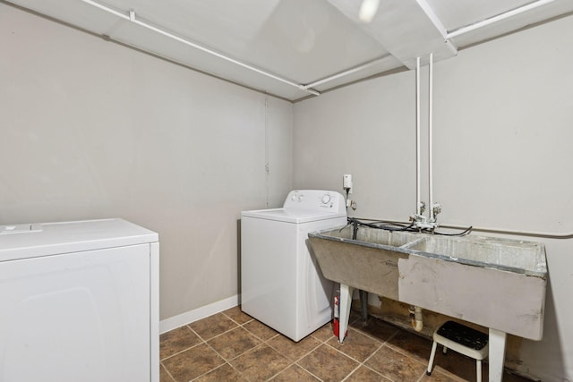 clothes washing area with laundry area, washing machine and dryer, and baseboards