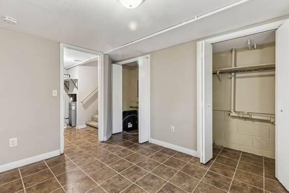 unfurnished bedroom featuring dark tile patterned flooring, a closet, and baseboards