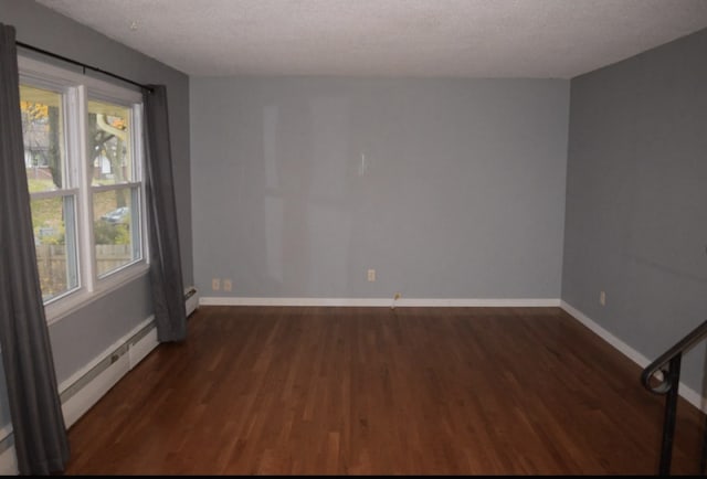 spare room featuring a baseboard radiator, baseboards, and wood finished floors