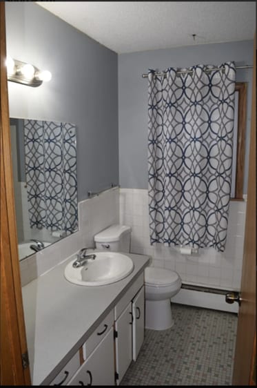 bathroom with tile walls, a baseboard radiator, toilet, wainscoting, and vanity