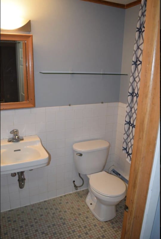 bathroom with wainscoting, toilet, and tile walls