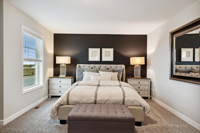 bedroom with baseboards, an accent wall, and light colored carpet