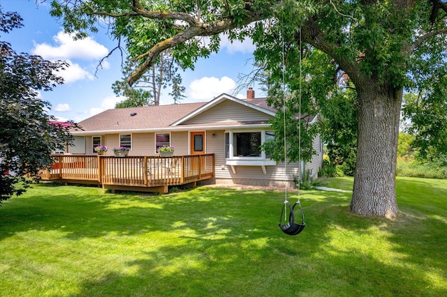 back of property with a deck, a yard, and a chimney