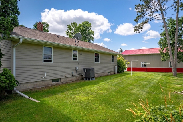 rear view of property with roof with shingles, a chimney, cooling unit, and a yard