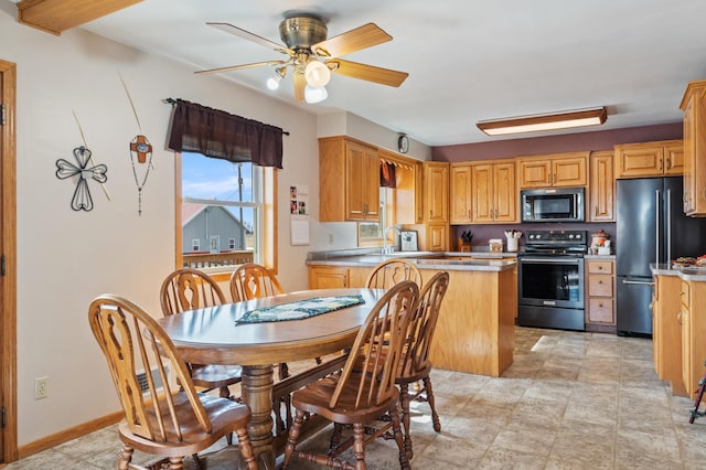 kitchen featuring baseboards, ceiling fan, appliances with stainless steel finishes, a peninsula, and a sink