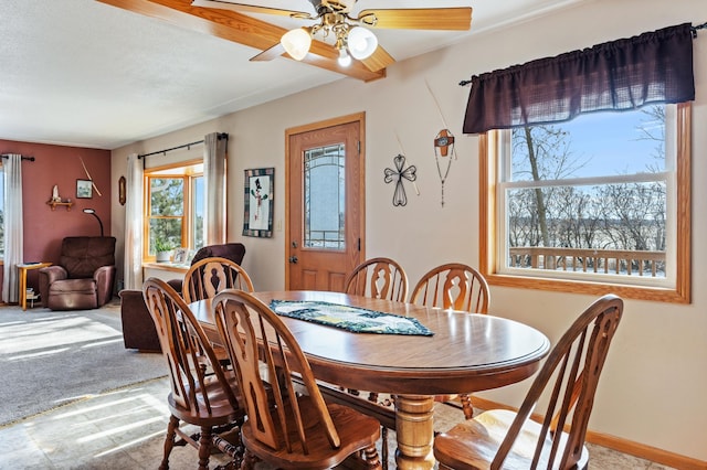 carpeted dining space with ceiling fan and baseboards