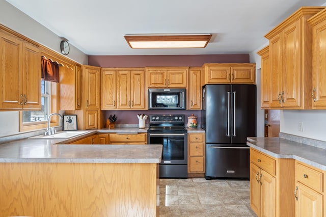 kitchen with a peninsula, black appliances, light countertops, and a sink