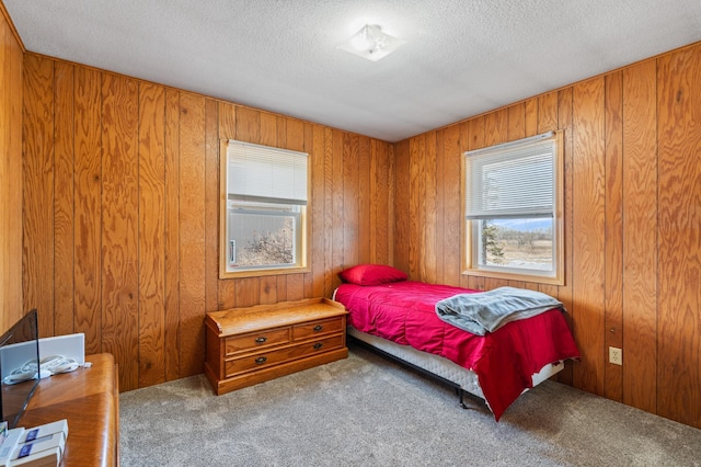 carpeted bedroom featuring wood walls and a textured ceiling