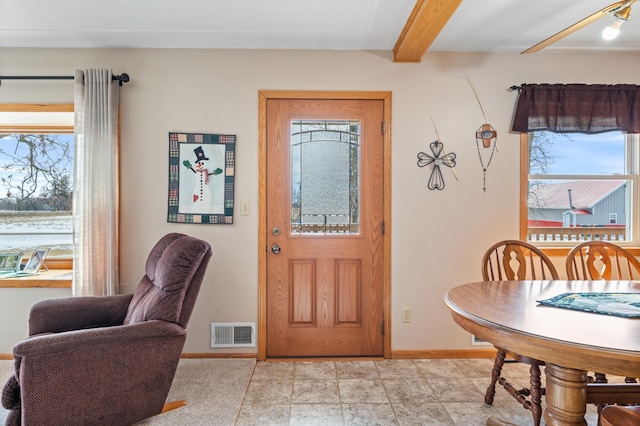 foyer entrance with beam ceiling, visible vents, and baseboards