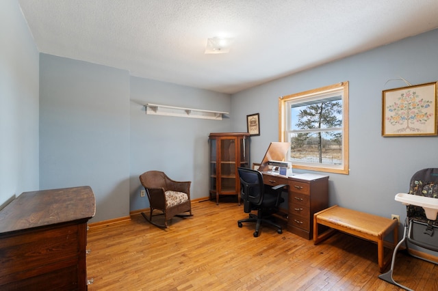 office space with light wood finished floors, baseboards, and a textured ceiling