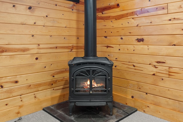 interior details with a wood stove, carpet flooring, and wooden walls