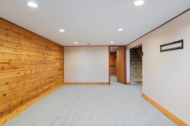 empty room with recessed lighting, wood walls, carpet flooring, baseboards, and stairs