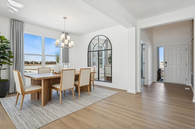 dining space featuring a chandelier, baseboards, and light wood finished floors