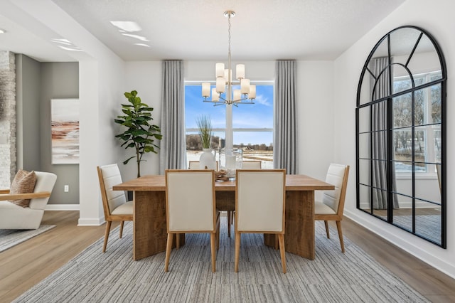 dining space with a chandelier, a textured ceiling, wood finished floors, and baseboards