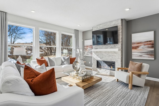 living area featuring recessed lighting, a fireplace, baseboards, and wood finished floors