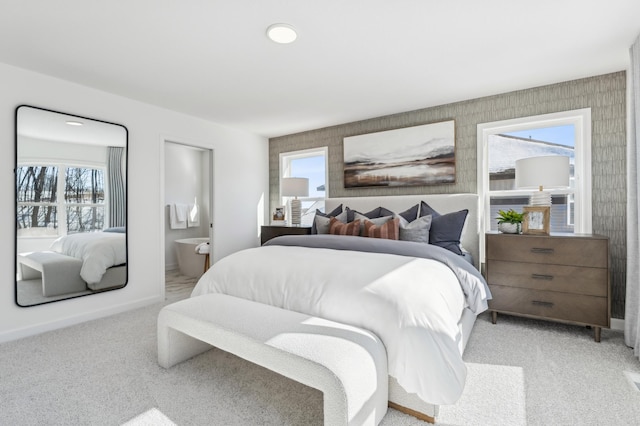 bedroom with light carpet, ensuite bathroom, and baseboards