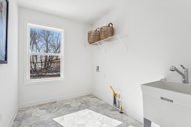 laundry area with laundry area, a sink, and baseboards