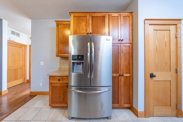 kitchen featuring light tile patterned floors, light countertops, stainless steel refrigerator with ice dispenser, and visible vents