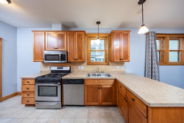 kitchen with appliances with stainless steel finishes, light countertops, a sink, and decorative backsplash