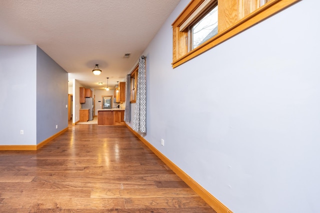 interior space featuring a textured ceiling, light wood-style flooring, and baseboards