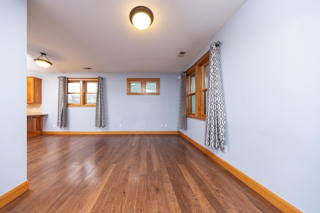 unfurnished room featuring baseboards, visible vents, and wood finished floors