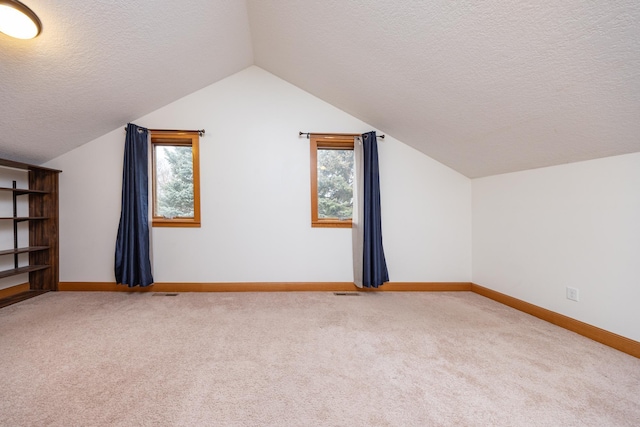 additional living space featuring a textured ceiling, baseboards, vaulted ceiling, and carpet flooring