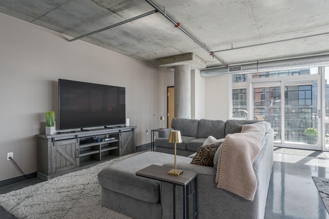 living area with finished concrete flooring, a wealth of natural light, and baseboards