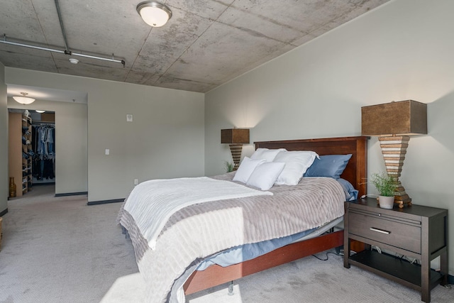 bedroom with a walk in closet, a closet, carpet flooring, and baseboards