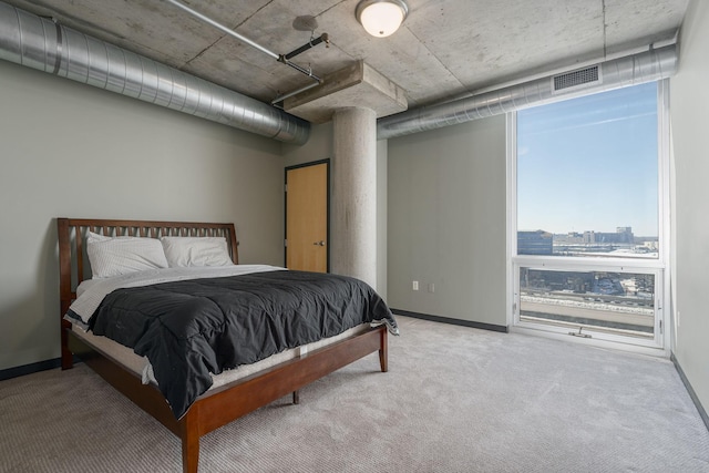 bedroom with baseboards, carpet, visible vents, and a city view