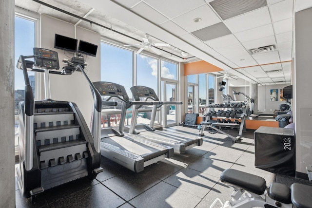 workout area with a ceiling fan, floor to ceiling windows, visible vents, and a drop ceiling