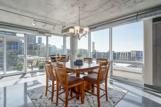 dining area with finished concrete flooring, an inviting chandelier, a wall of windows, and a city view