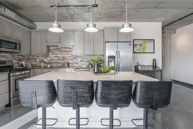 kitchen with light stone countertops, a kitchen island, appliances with stainless steel finishes, and a kitchen breakfast bar