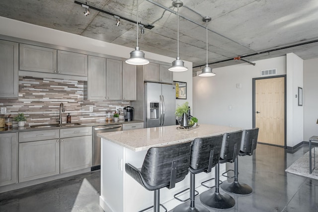 kitchen featuring a sink, visible vents, finished concrete flooring, appliances with stainless steel finishes, and tasteful backsplash